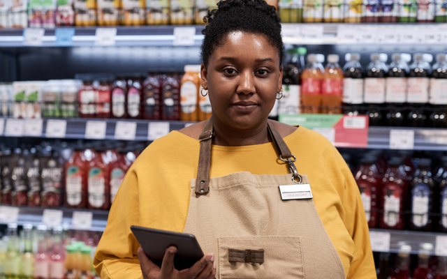 Supermarket employee with tablet, supporting frontline work; no visible UI or relevant keywords.