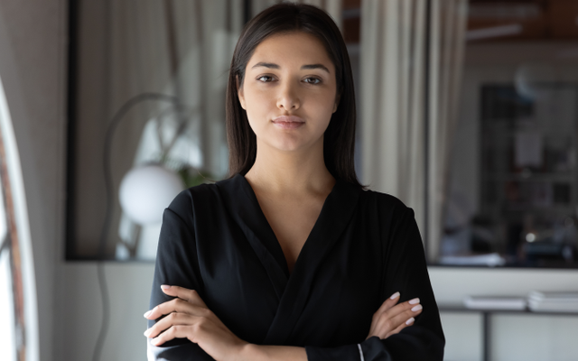 Professional woman in office, arms crossed, no visible UI; image is decorative, no text shown.