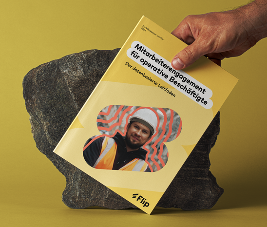 Hand hält Flip-Whitepaper „Mitarbeiterengagement für operative Beschäftigte“ vor gelbem Hintergrund.