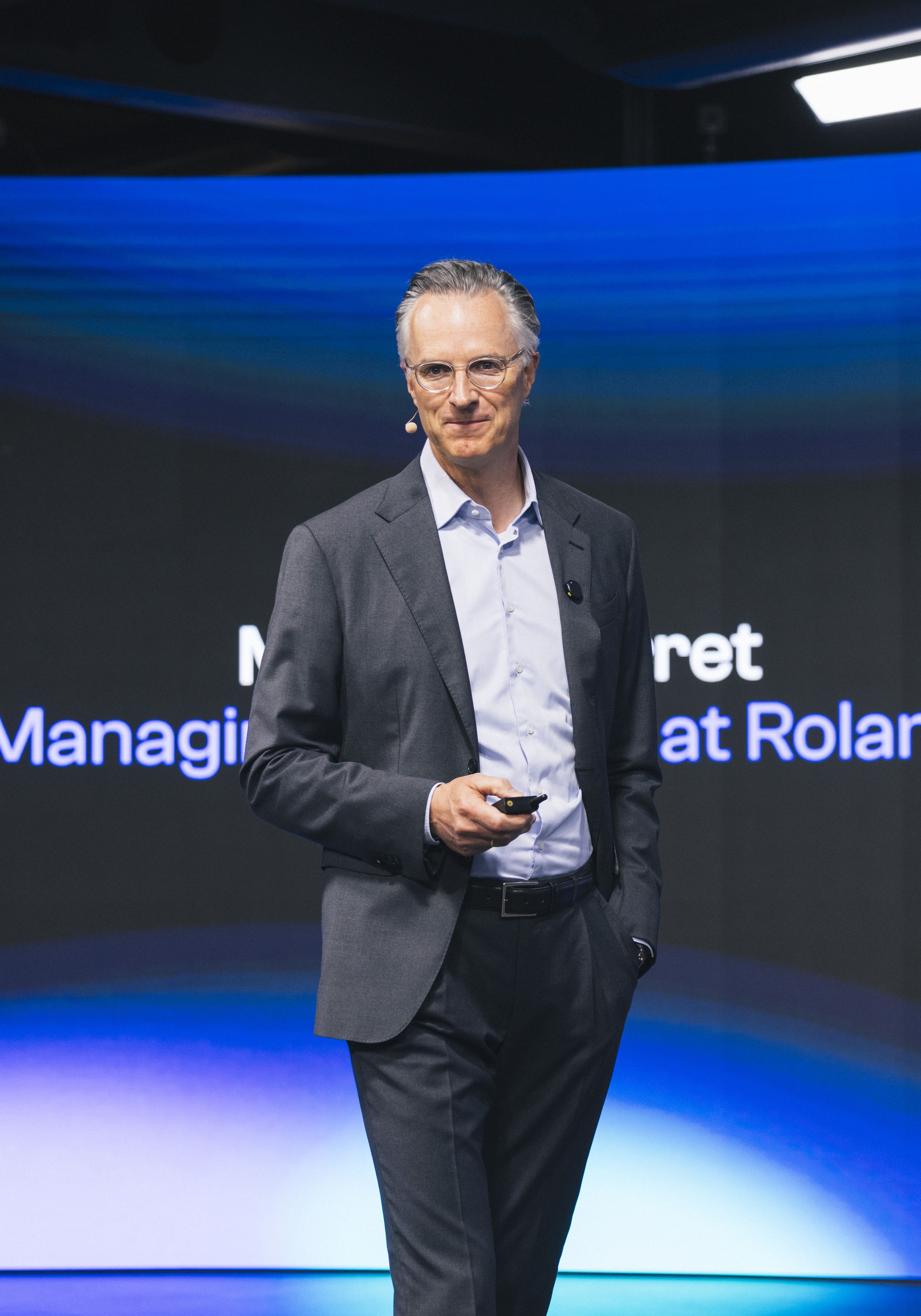 Person on stage with text: Global Managing at Roland Berger.