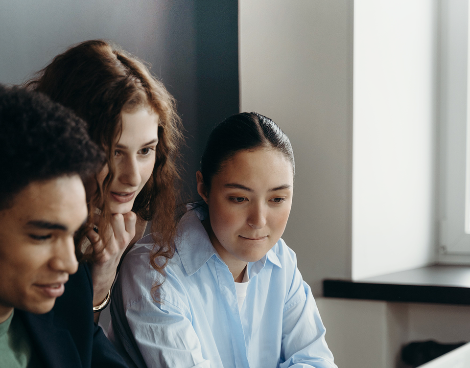 Three people collaborating at a laptop, no visible UI; modern teamwork, trends, digital workspace.