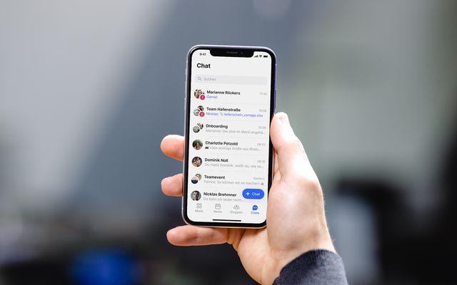 Hand hält Smartphone mit Mitarbeiter App Chat-Übersicht, Mitarbeiterplattform, Employee Engagement.