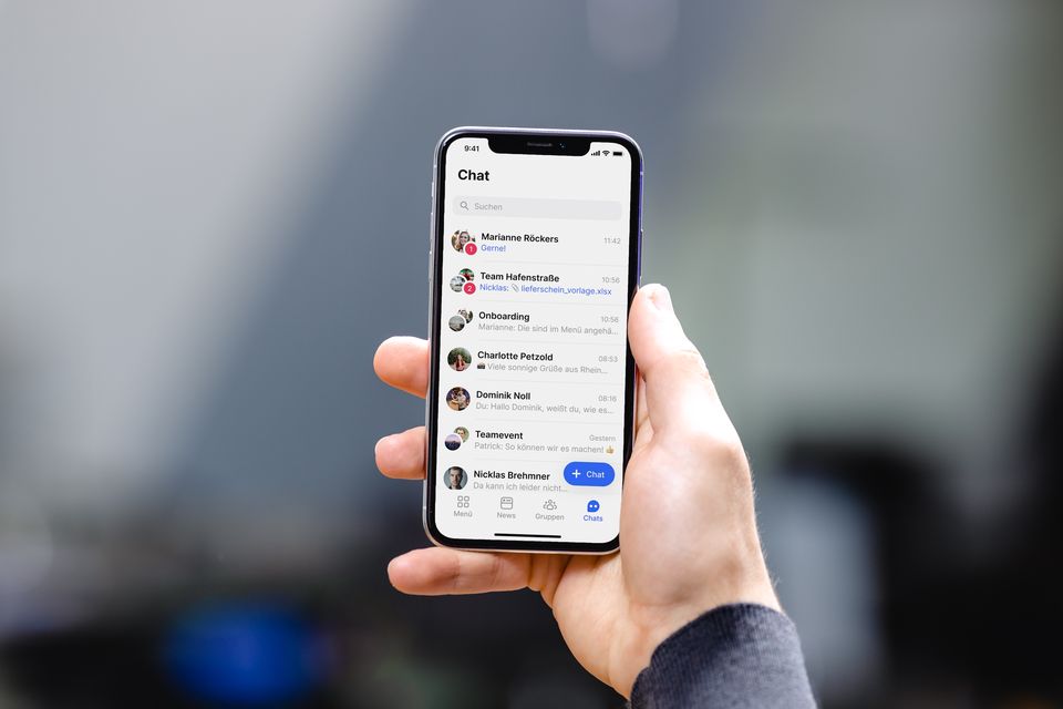 Hand hält Smartphone mit Mitarbeiter App Chat-Übersicht, Mitarbeiterplattform, Employee Engagement.