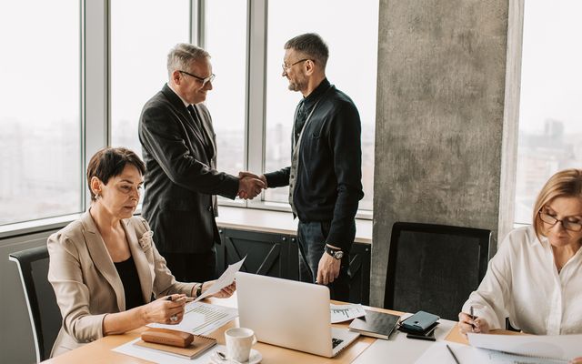 Business professionals in office, two men shaking hands, teamwork, partnership, handshake, meeting.