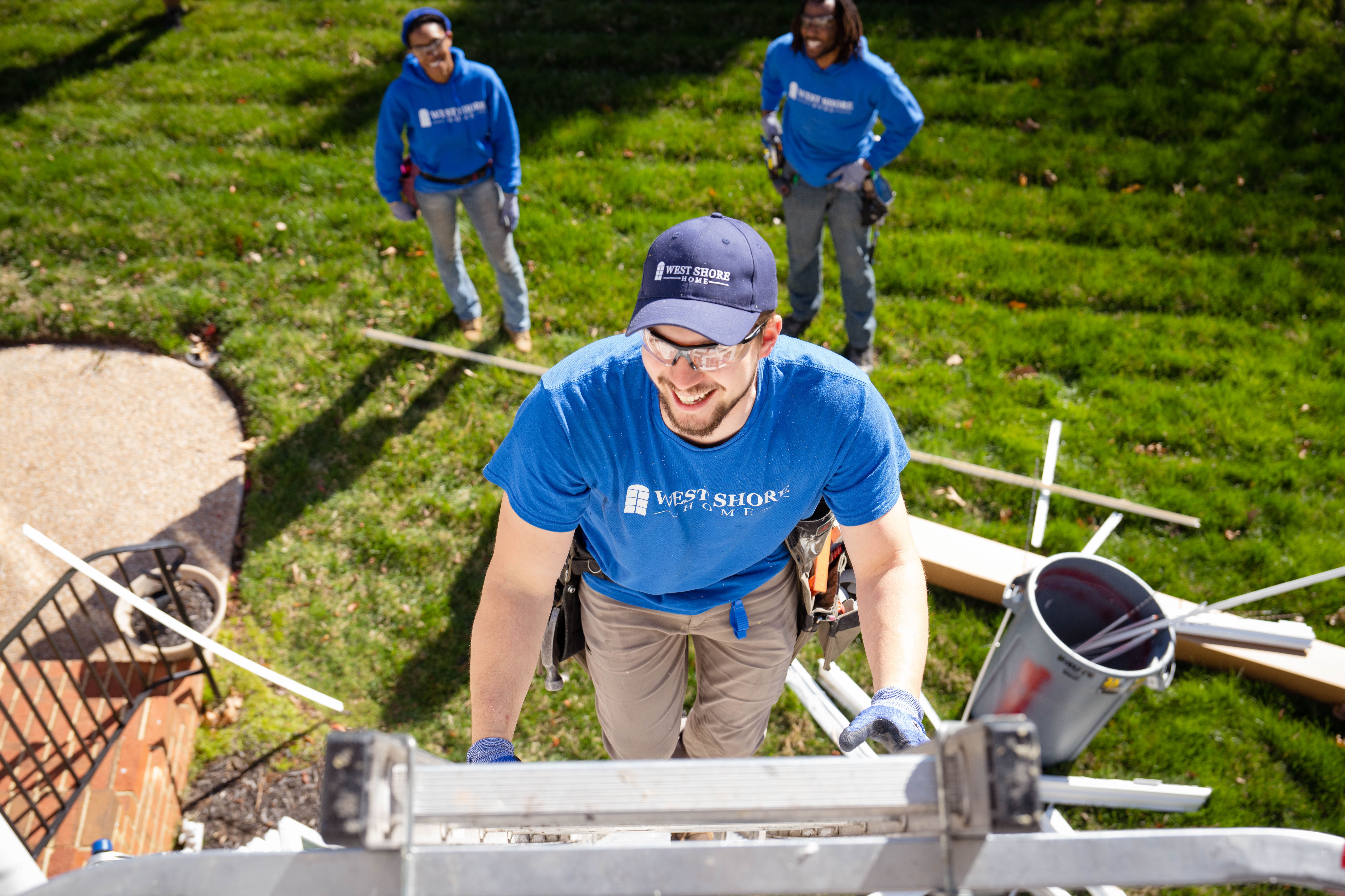 An installer in West Shore Home attire climbing a ladder.
