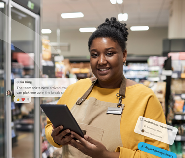 A store employee in an apron holds a tablet, with digital notifications floating around her in a grocery store setting.