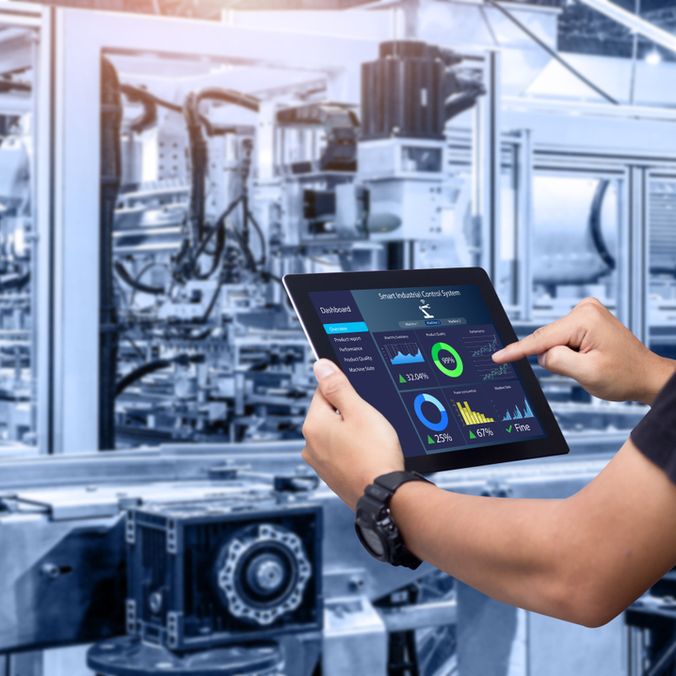Person uses tablet with Smart Industrial Control System dashboard to boost manufacturing productivity.