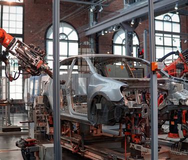 Roboterarme montieren ein Auto in einer modernen Automobilfabrik, industrielle Automatisierung.