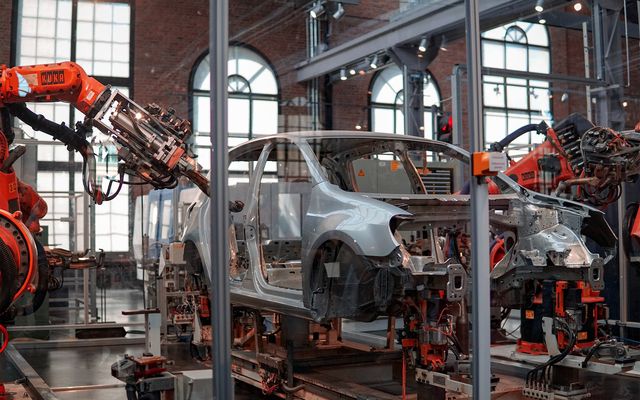Roboterarme montieren ein Auto in einer modernen Automobilfabrik, industrielle Automatisierung.