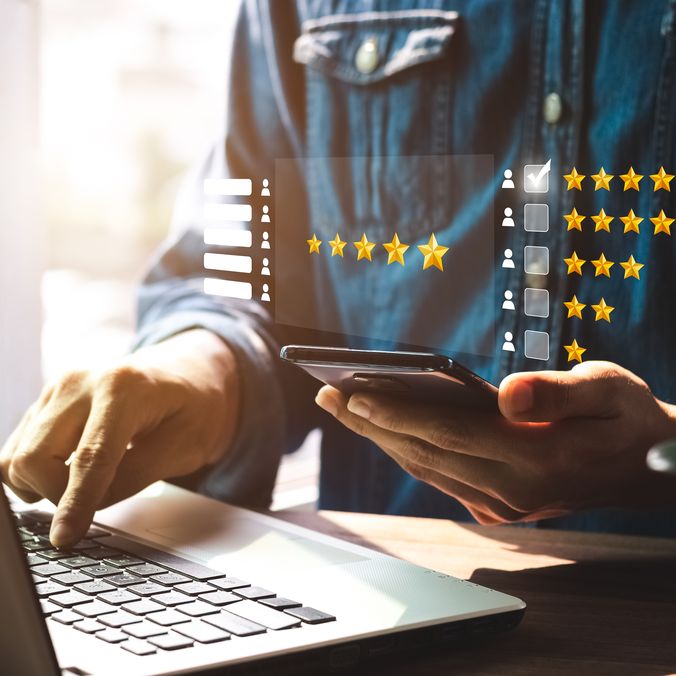 Person using phone and laptop with floating star ratings.