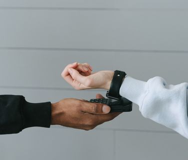 Person scanning smartwatch with payment terminal, contactless technology, modern wearable device.