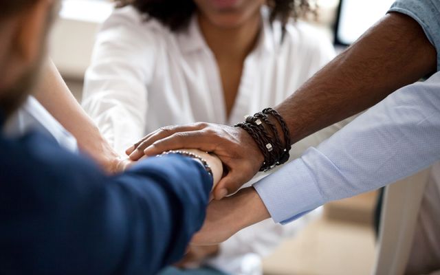 Diverse team joining hands, symbolizing unity, collaboration, and employee engagement.
