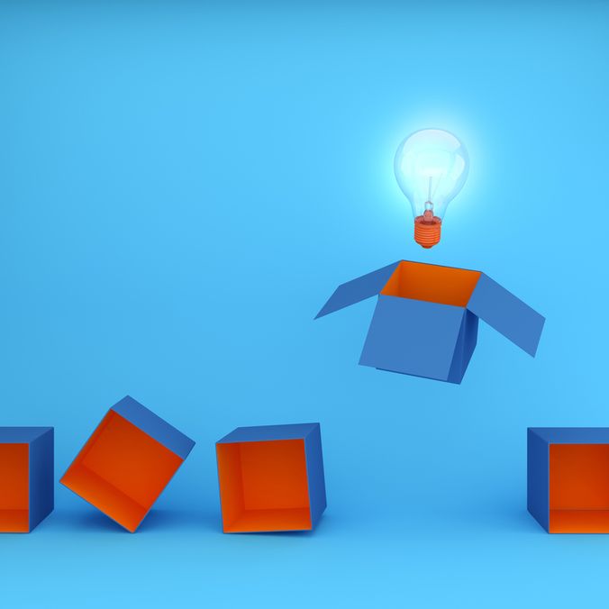 Four blue-orange boxes, one open with a glowing lightbulb above, symbolizing creative ideas.