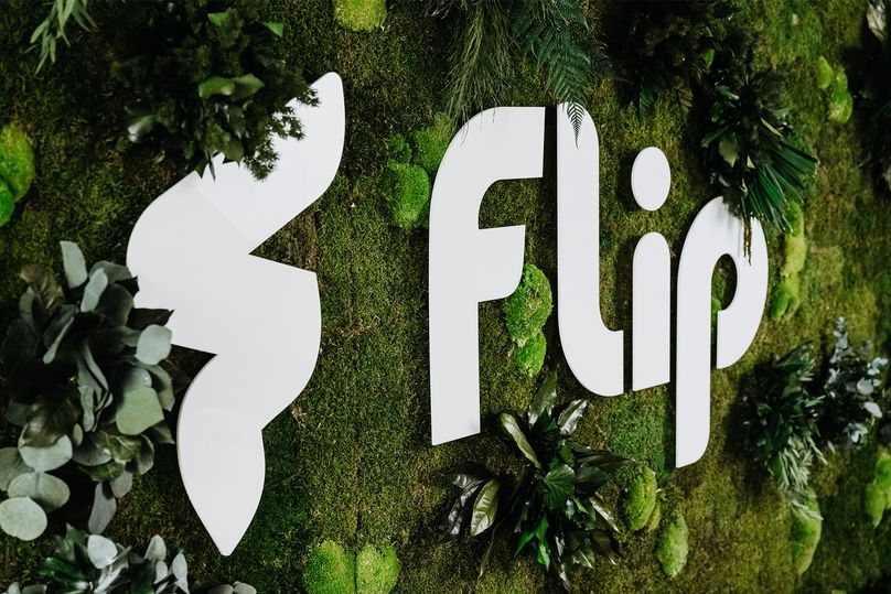 Large Flip logo on a green, plant-covered wall; decorative branding display.