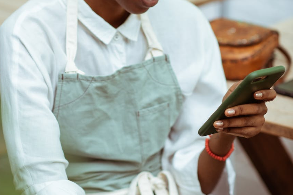Worker in apron using a mobile phone, representing frontline employee digital empowerment.