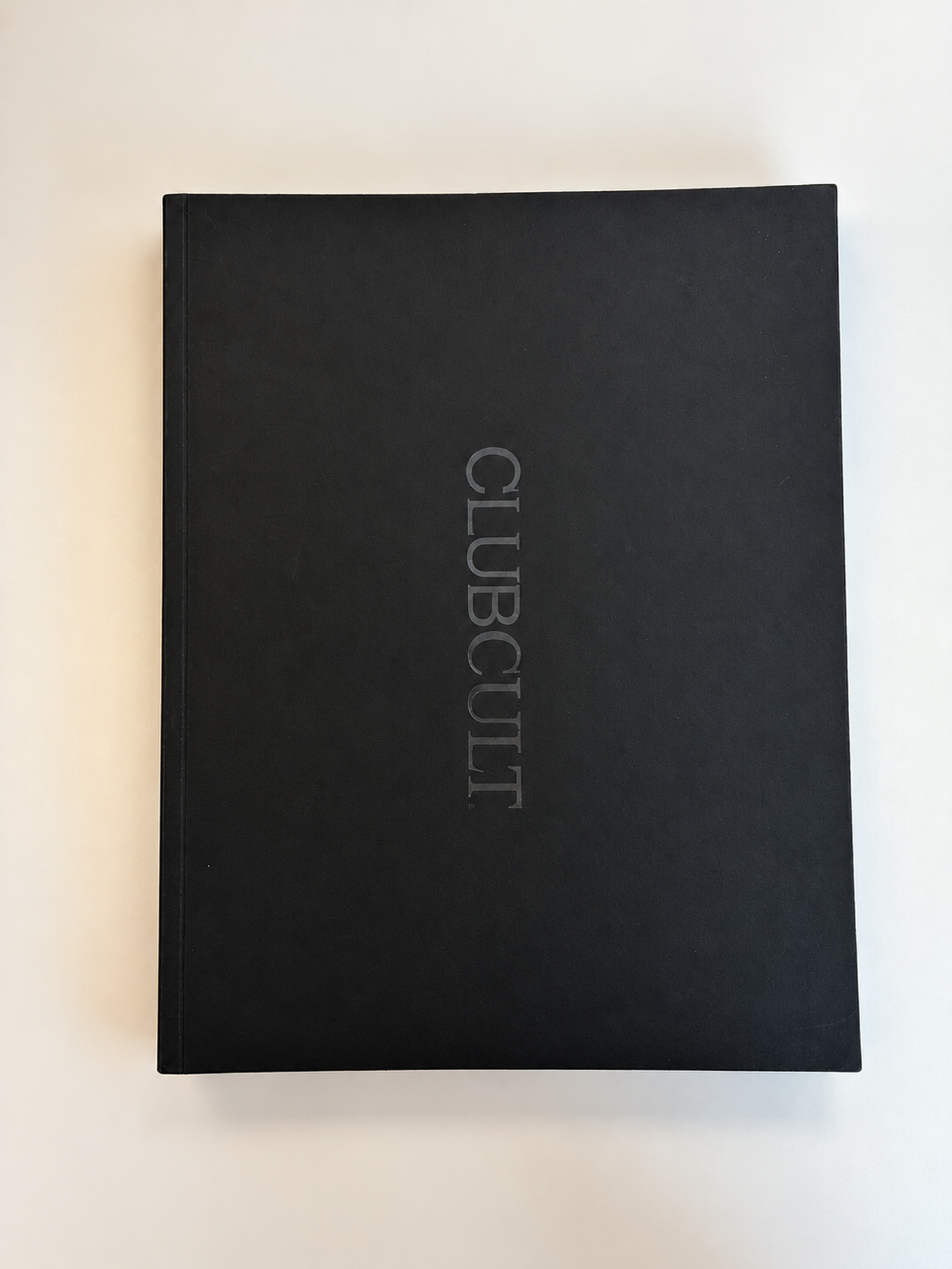 A black book with the title "CLUBCULT" embossed in vertical silver letters on the cover, placed on a white background.