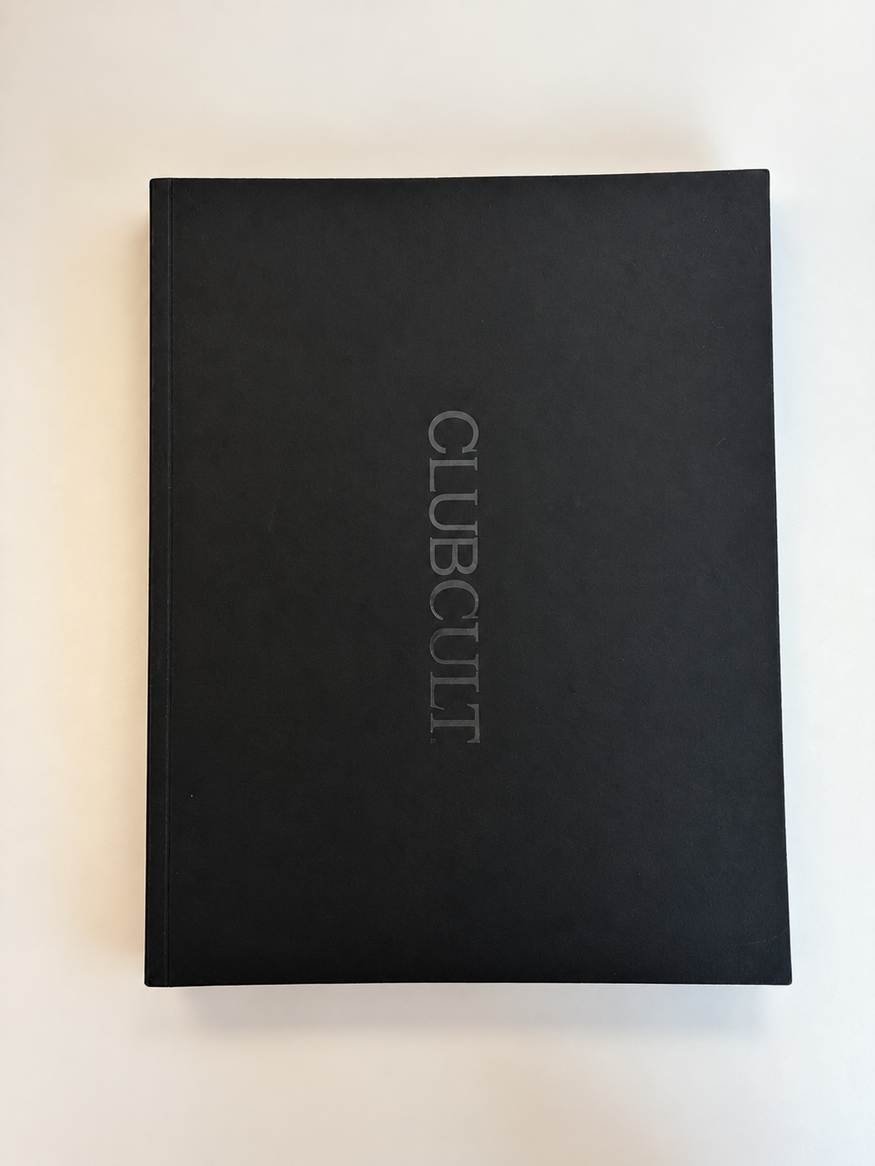 A black book with the title "CLUBCULT" embossed in vertical silver letters on the cover, placed on a white background.