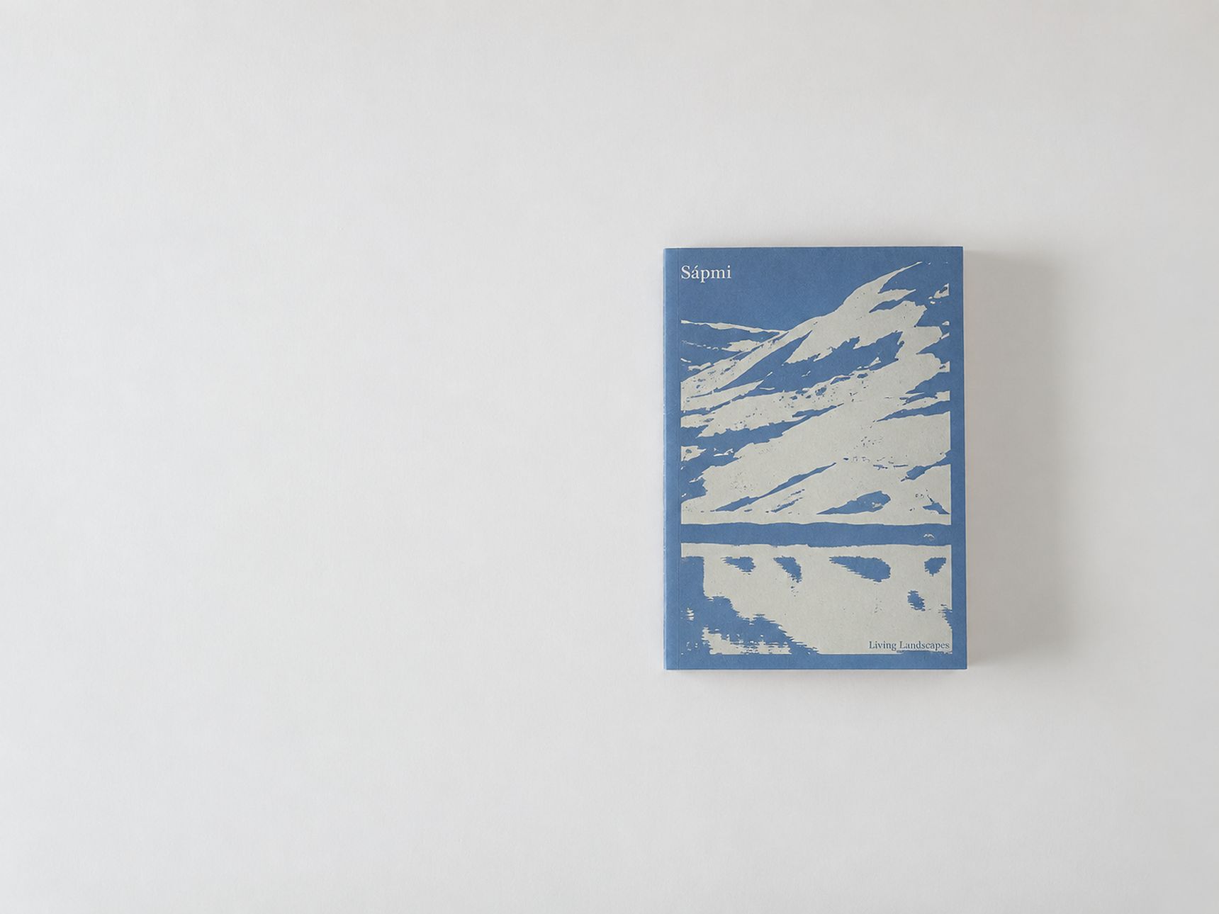 A book titled "Sápmi" with blue cover art depicting abstract mountains and landscape, placed on a plain white background.
