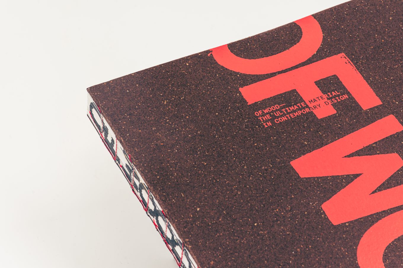 Close-up of a book corner with a cork-textured cover featuring bold red typography, partially visible text, and a unique exposed spine binding.