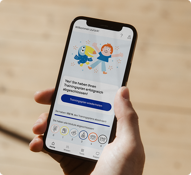 Foto-Mockup einer Hand, die ein Smartphone hält, auf dessen hiToco-Bildschirm der Nutzer die Trainingsplan-Module abgeschlossen hat.