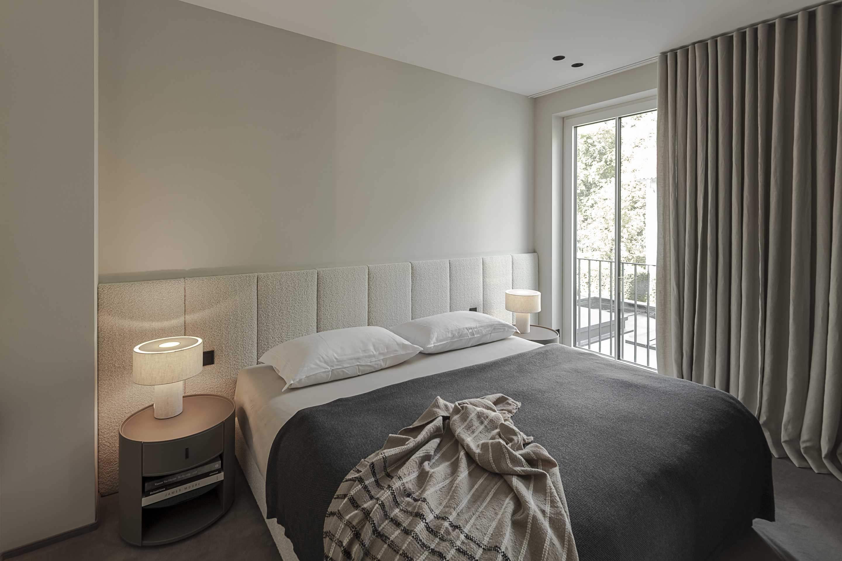 Loft G München: Schlafzimmer mit gepolstertem Betthaupt und Teppichboden Seitenansicht