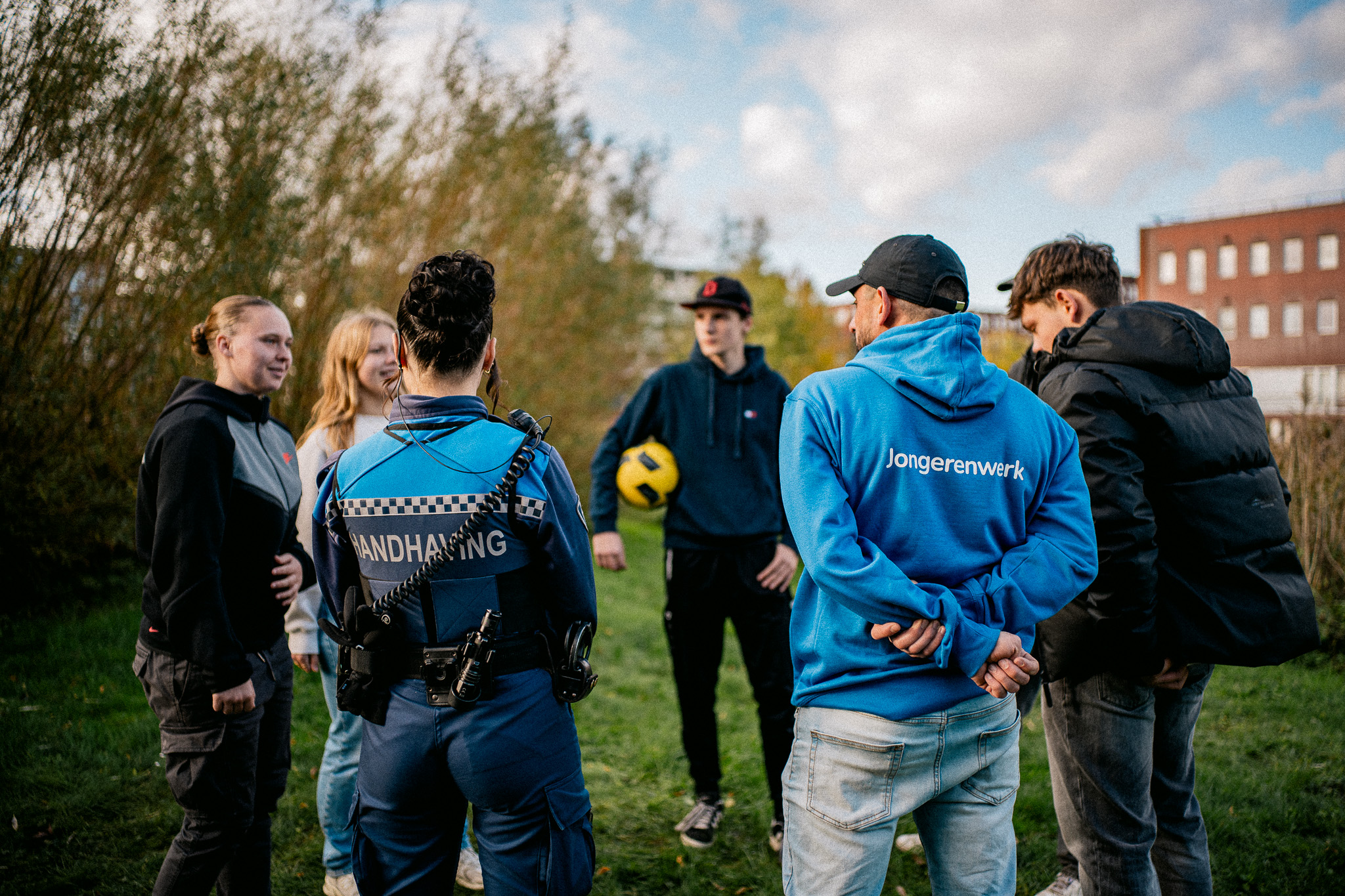 Jongerenwerker met Jeugdboa in gesprek met met jongeren met een voetbal