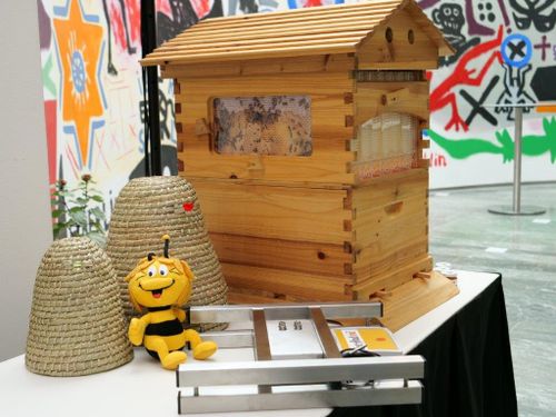 A bee figure sits next to a bee house