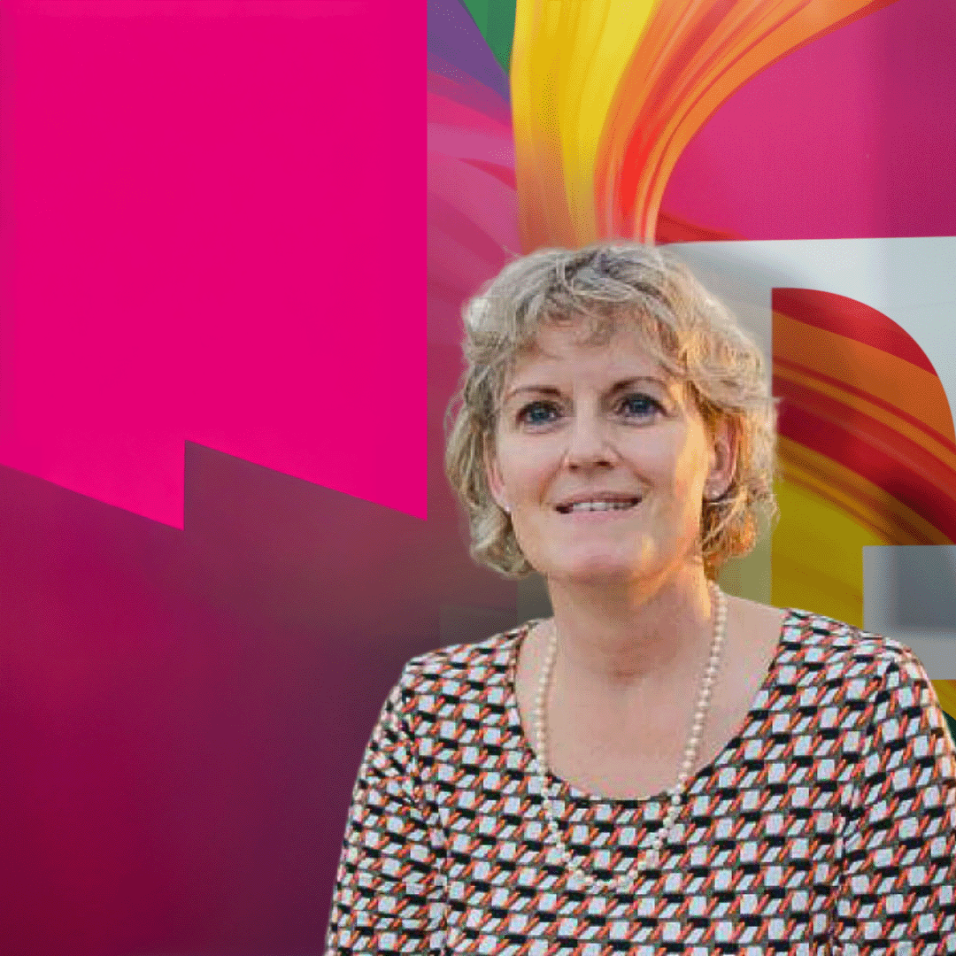 A person with short curly hair, wearing a patterned top and necklace, stands in front of a colorful abstract background.