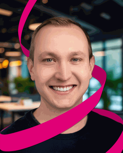 Smiling person with short hair, surrounded by a pink ribbon, in a modern office setting with blurred background.