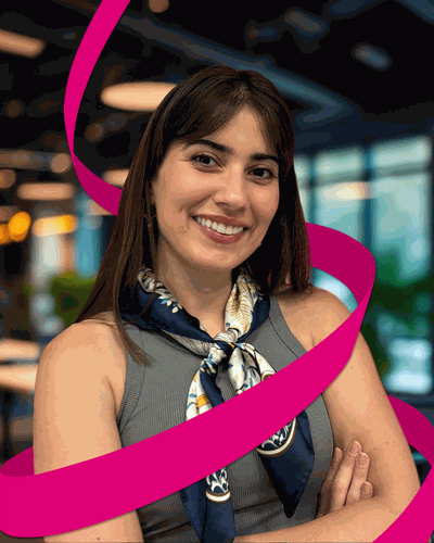 Smiling woman with crossed arms wearing a scarf, standing indoors with a blurred background and a swirling pink ribbon effect.