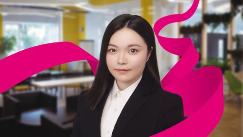 A person in a black suit and white shirt is standing in a modern office with magenta graphic ribbons.