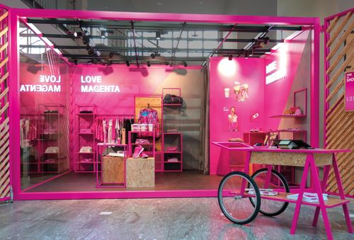 A vibrant magenta retail display features clothing, accessories, and a cart, with "LOVE MAGENTA" illuminated on the wall.