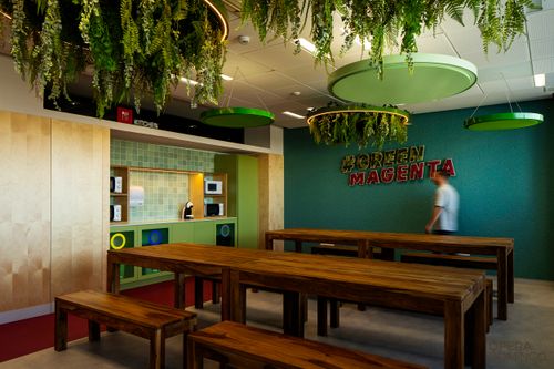 Modern kitchen space with wooden tables, green tile backsplash, hanging plants, and "#GREEN MAGENTA" text on teal wall.