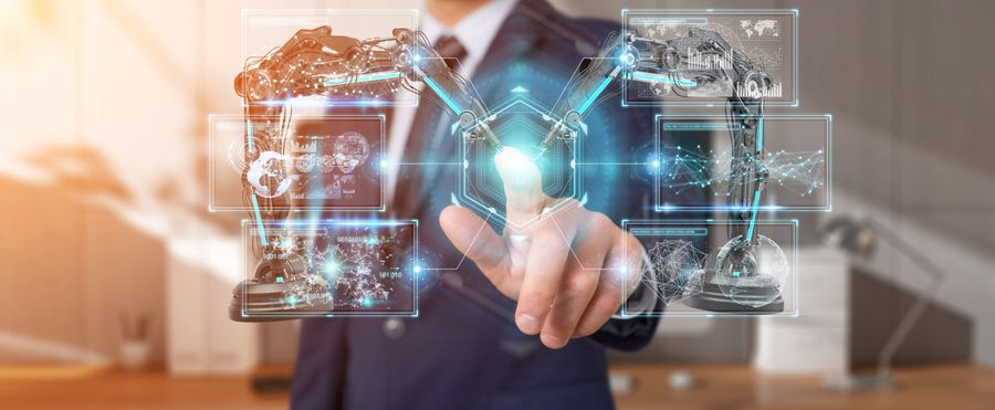 Person in a suit interacting with a virtual interface displaying robotic arms and digital graphics in a modern office setting.