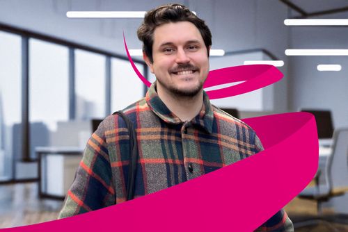 Smiling man in a plaid jacket stands in a modern office with large windows. A magenta ribbon graphic swirls around him.