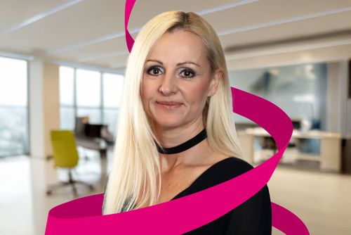 A woman with long blonde hair and a black choker stands in a modern office, with a magenta ribbon graphic swirling around her.