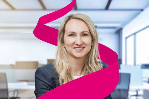 Smiling woman with long blonde hair in an office setting, wrapped by a magenta ribbon graphic.