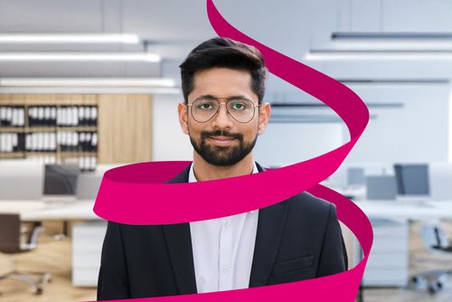 A man in a suit with glasses stands in an office, with a pink ribbon spiraling around him.