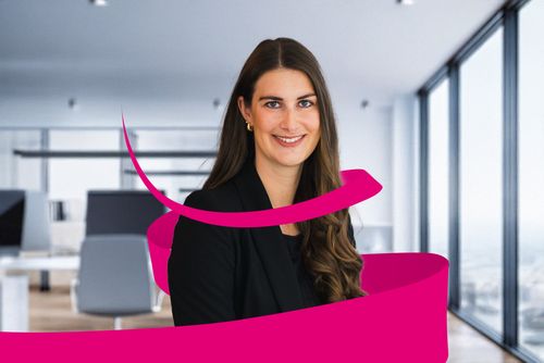 Smiling woman in a black blazer with long hair, standing in a modern office with large windows. Pink ribbon design overlays the image.