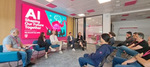 Panel discussion at "AI Shaping Our Future Together" event with attendees and a large pink digital screen in the background.