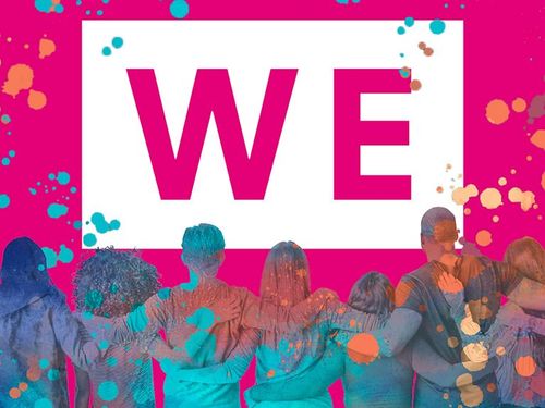 A diverse group of people stand arm in arm, facing a large "WE" sign on a vibrant pink background with colorful paint splatters.