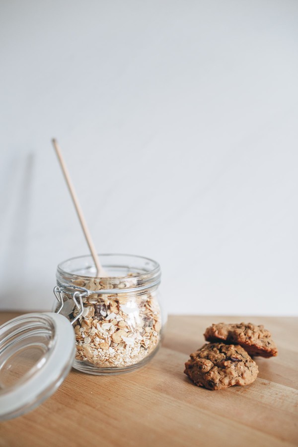 Deux cookies au muesli posés à côté d'un pot de flocons d'avoine
