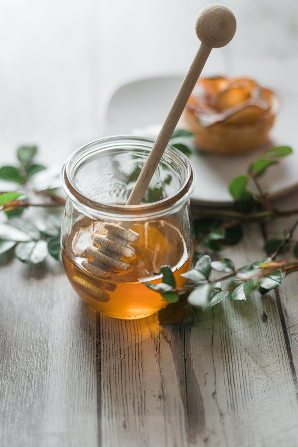 Pot de miel en verre sur une table avec un dessert en arrière plan