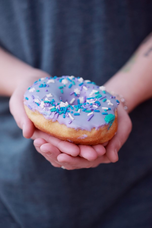 Gros plan sur un donut avec un nappage violet et des pastilles de sucre
