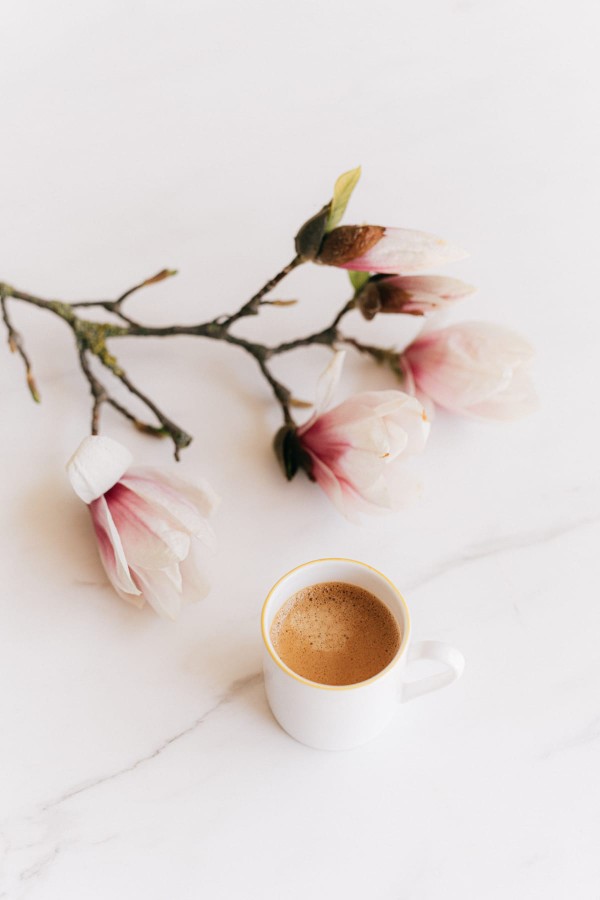 Mug de café pour le petit-déjeuner, sur une table à côté de fleurs coupées