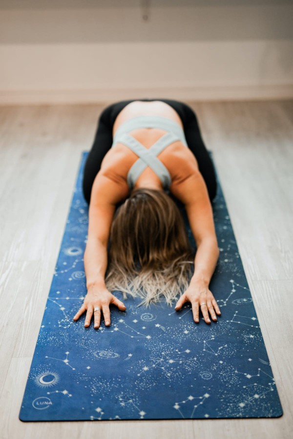 Jeune femme pratiquante de yoga en posture de l'enfant sur son tapis