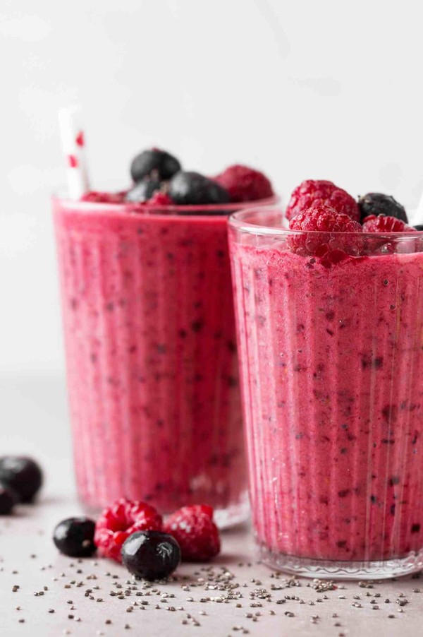 Deux verres de smoothie aux fruits rouges avec des framboises et des myrtilles