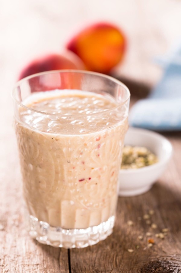 Verre de smoothie riche en fer à la pêche et à la noix de coco riche sur une table de petit-déjeuner