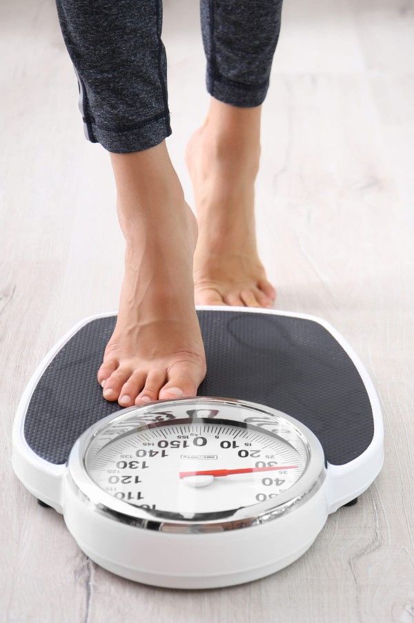 Jeune femme se pesant sur une balance