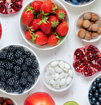 Exemples d'aliments riches en fibres pour le petit-déjeuner, comme des fraises, des noisettes et des fruits rouges